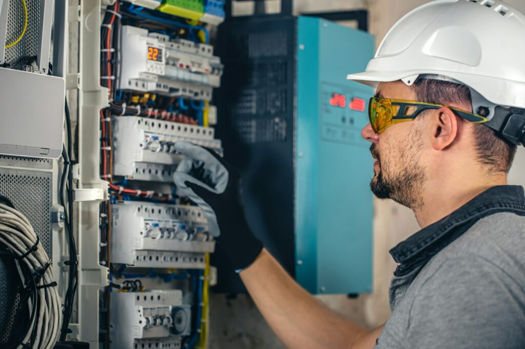 Man, an electrical technician working in a switchboard with fuses.